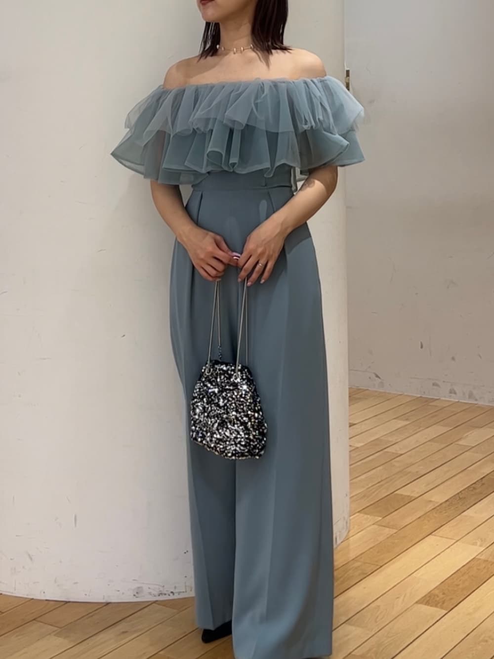 シルバー系のショルダーバッグ、ブラック系のパンプス、ブルー系のパンツドレスを着用したレディースの春コーディネートの4枚目の写真
