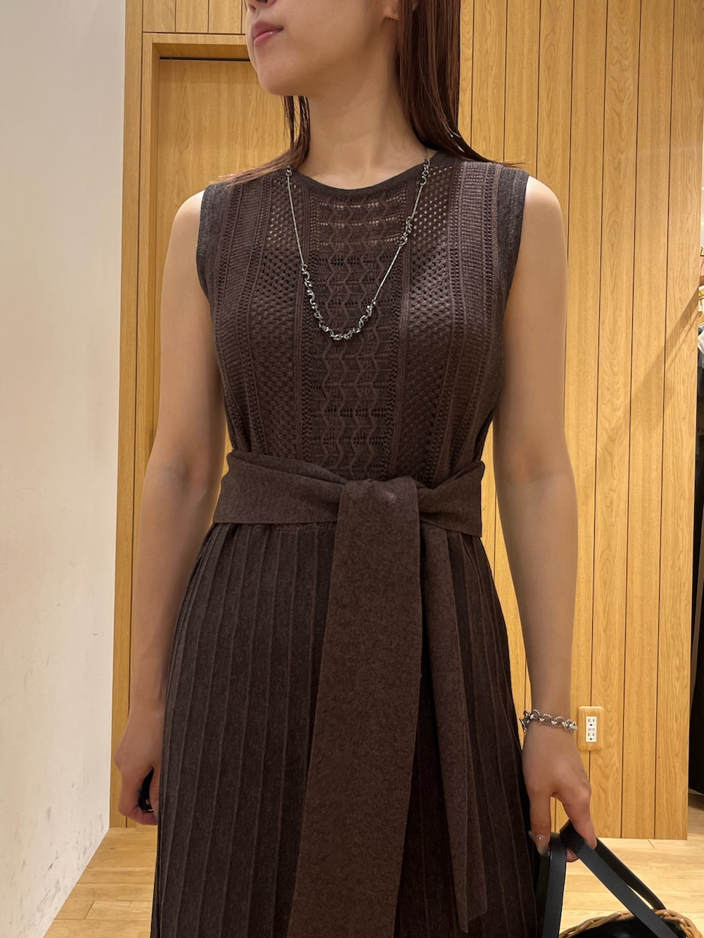 ブラウン系のハンドバッグ、ブラウン系のワンピース、シルバー系のネックレスを着用したレディースの夏コーディネートの5枚目の写真