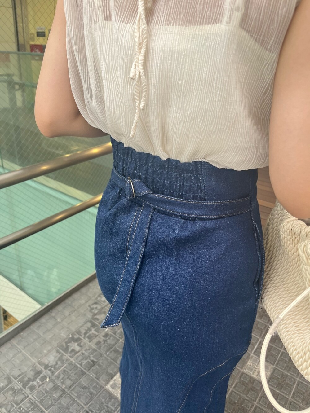 ブルー系のシャツ/ブラウス、ブルー系のデニムスカート、ベージュ系のハンドバッグを着用したレディースの夏コーディネートの5枚目の写真