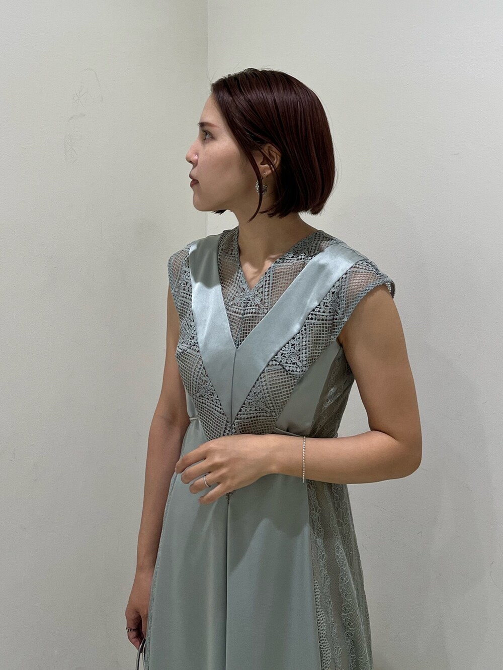 シルバー系のハンドバッグ、ブラック系のパンプス、グリーン系のドレスを着用したレディースの秋コーディネートの5枚目の写真