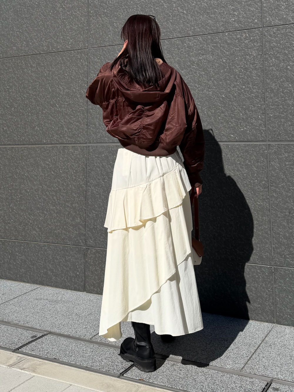 ブラック系のニット/セーター、ホワイト系のスカート、ブラウン系のブルゾンを着用したレディースの冬コーディネートの3枚目の写真