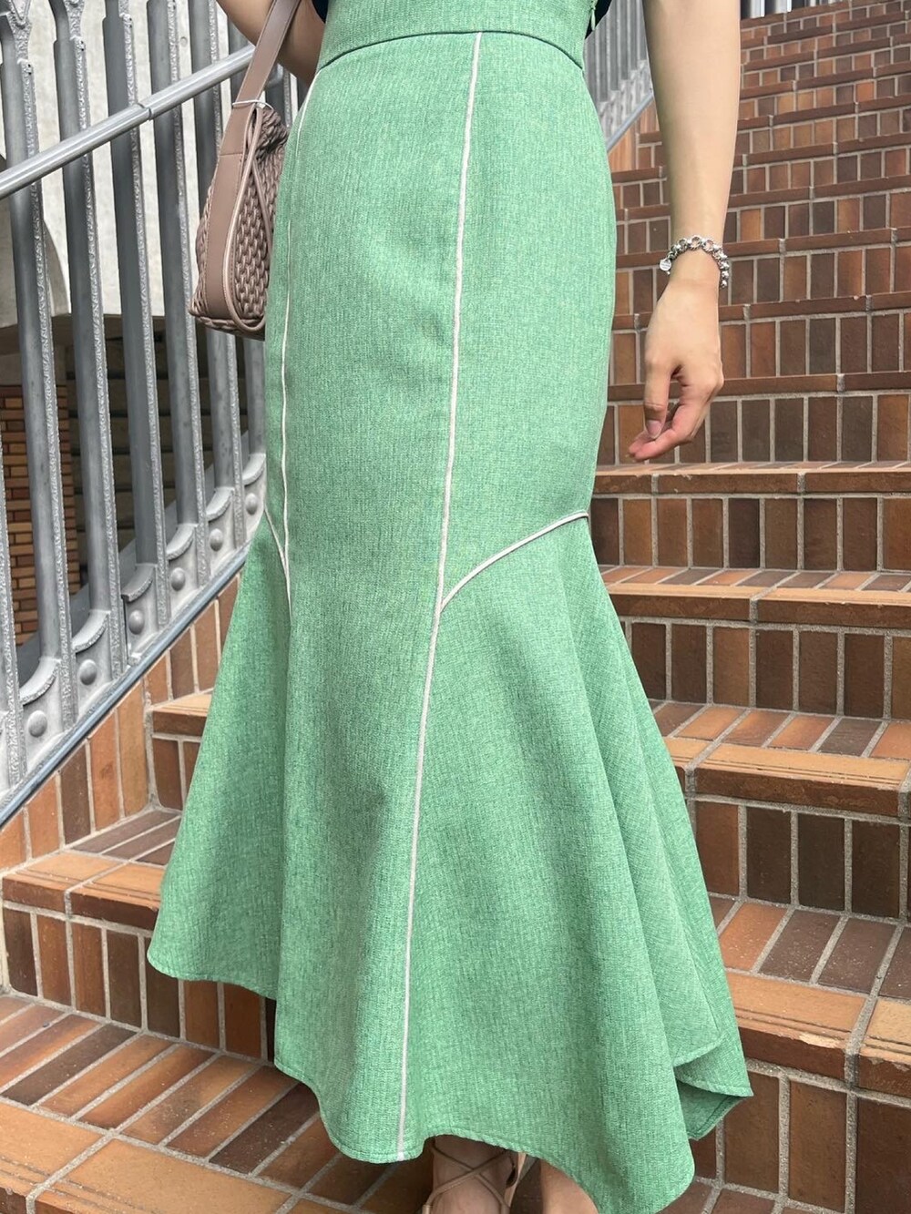 ブラック系のニット/セーター、グリーン系のスカート、ベージュ系のサンダルを着用したレディースの夏コーディネートの3枚目の写真