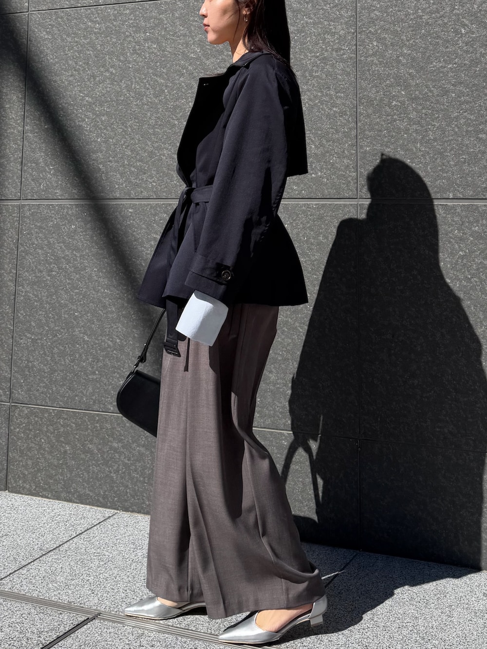 ブルー系のトレンチコート、グレー系のその他パンツ、ブラック系のハンドバッグを着用したレディースの冬コーディネートの2枚目の写真