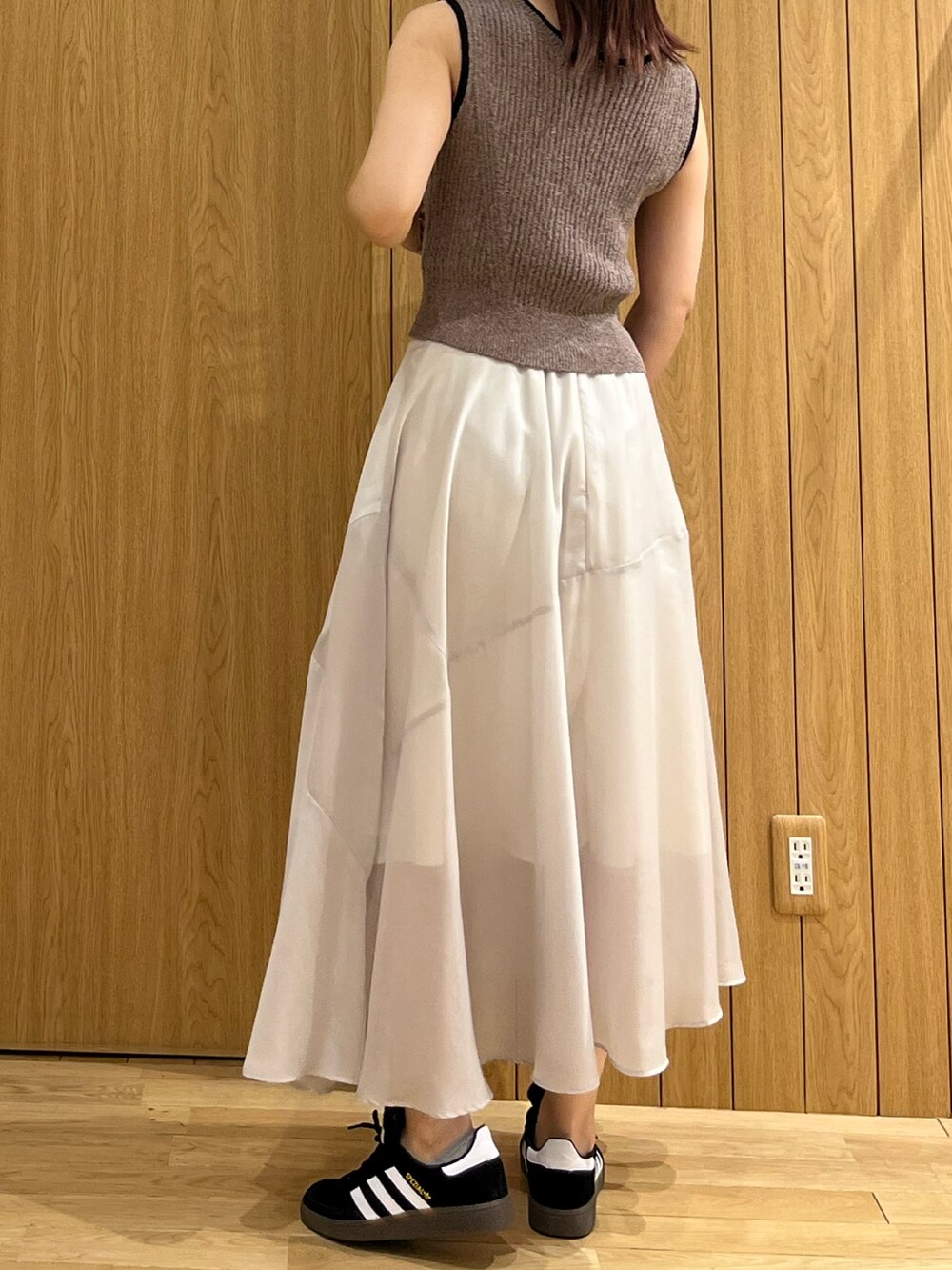 ブラウン系のニット/セーター、グレー系のスカート、ブラック系のスニーカーを着用したレディースの春コーディネートの6枚目の写真