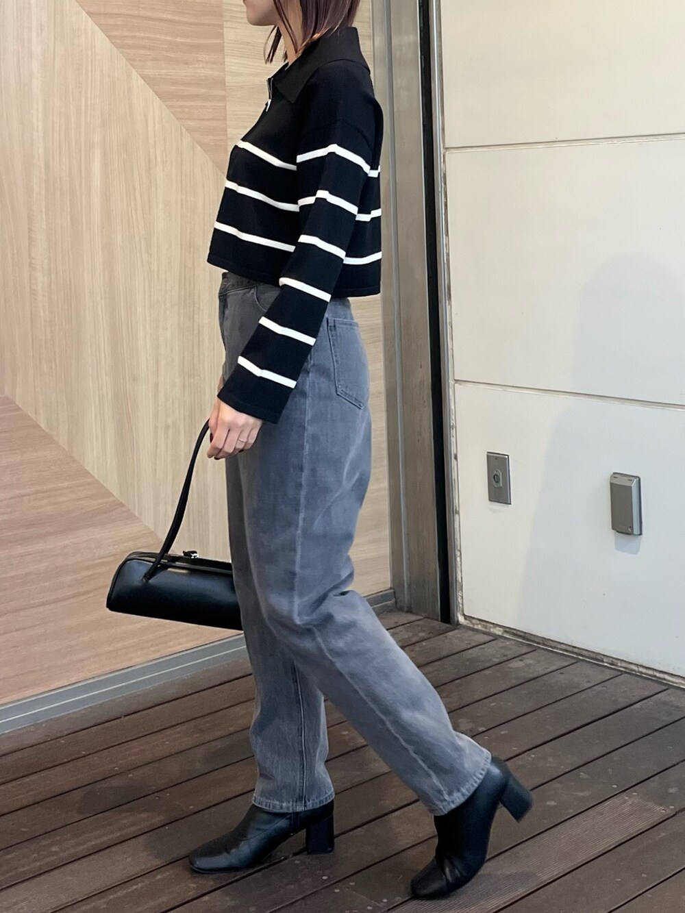 ブラック系のデニムパンツ、ブラック系のニット/セーター、ブラック系のショルダーバッグを着用したレディースの冬コーディネートの2枚目の写真