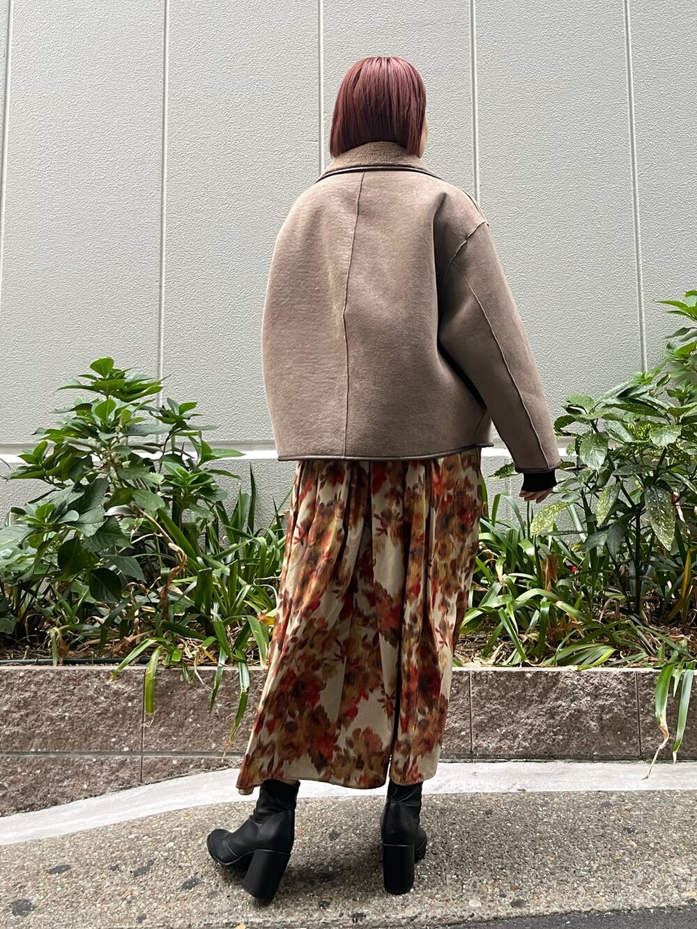 オレンジ系のスカート、ベージュ系のムートンコート、ブラック系のニット/セーターを着用したレディースの秋コーディネートの3枚目の写真