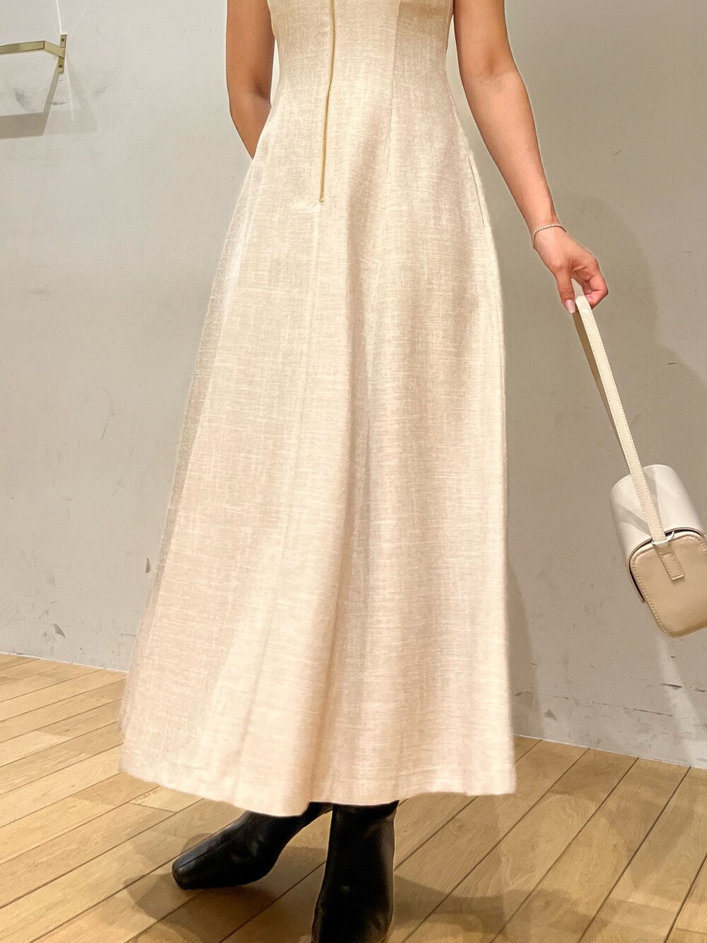 ホワイト系のショルダーバッグ、ベージュ系のワンピース、ブラック系のブーツを着用したレディースの夏コーディネートの4枚目の写真