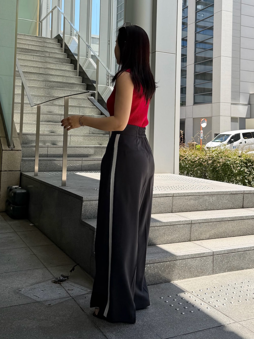 グレー系のその他パンツ、レッド系のニット/セーター、ブラウン系のハンドバッグを着用したレディースの春コーディネートの2枚目の写真