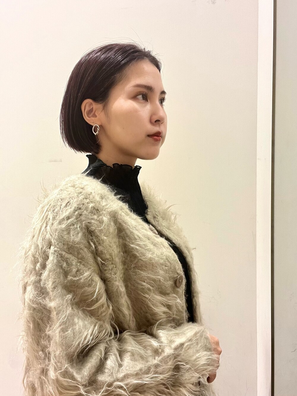 ホワイト系のハンドバッグ、ブラック系のデニムパンツ、ベージュ系のブーツを着用したレディースの秋コーディネートの2枚目の写真