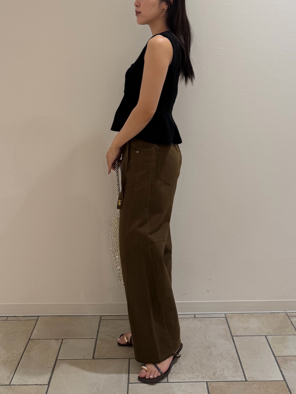ブラック系のニット/セーター、ブラウン系のデニムパンツ、ブラウン系のサンダルを着用したレディースの夏コーディネートの2枚目の写真