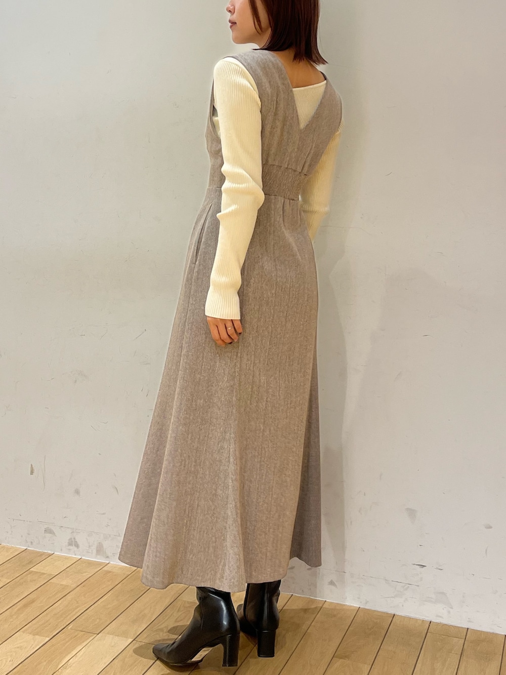 ブラック系のブーツ、ホワイト系のニット/セーター、ベージュ系のジャンパースカートを着用したレディースの冬コーディネートの3枚目の写真