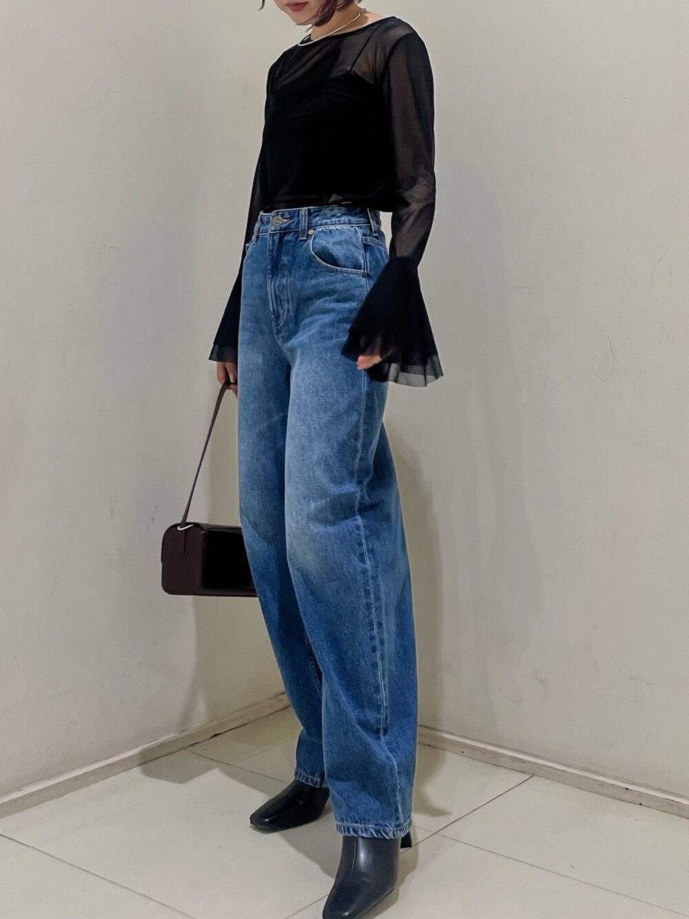 ブルー系のデニムパンツ、レッド系のショルダーバッグ、ブラック系のブーツを着用したレディースの秋コーディネートの2枚目の写真