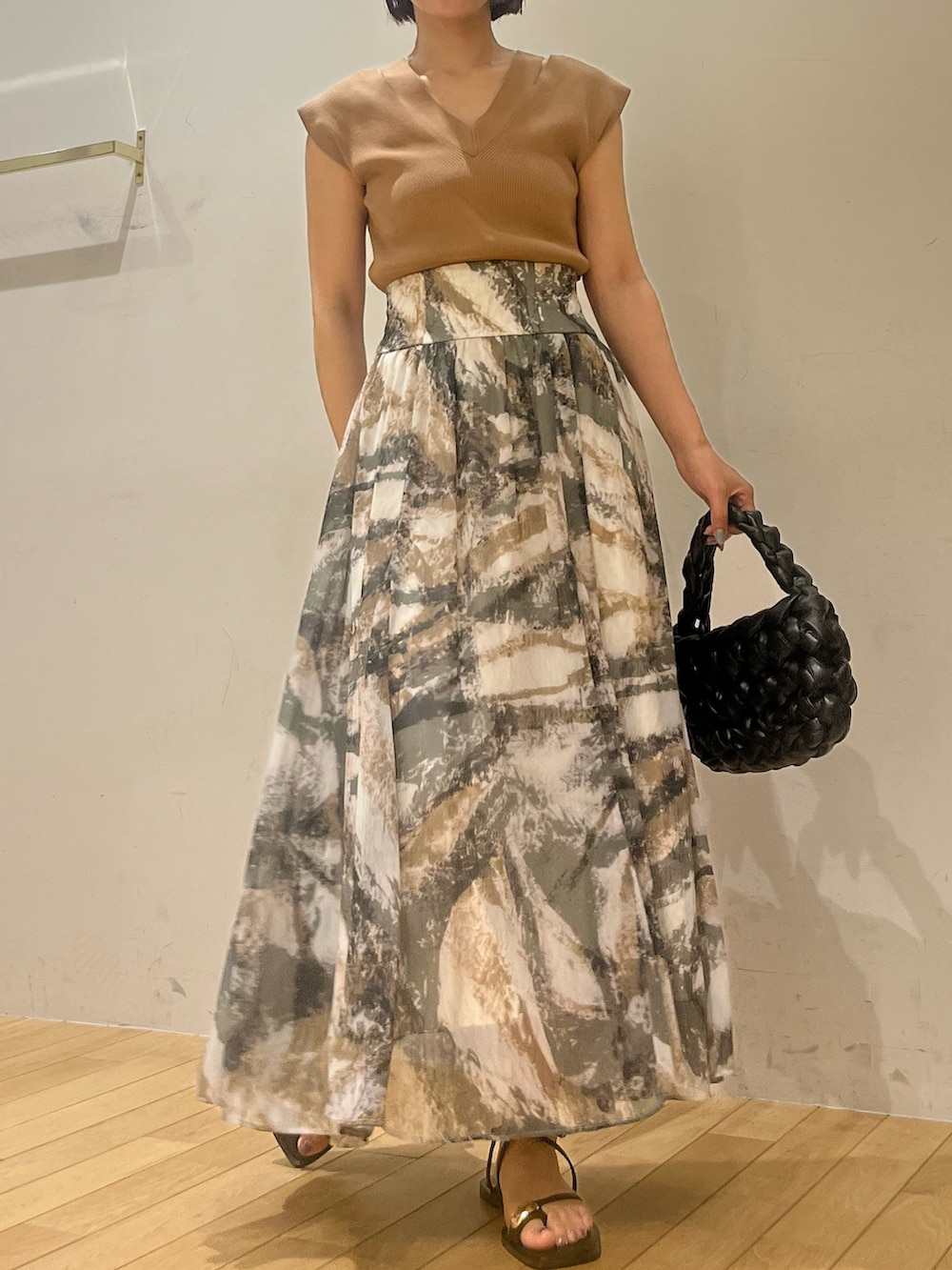 グレー系のスカート、ブラウン系のニット/セーター、ブラック系のサンダルを着用したレディースの夏コーディネートの2枚目の写真