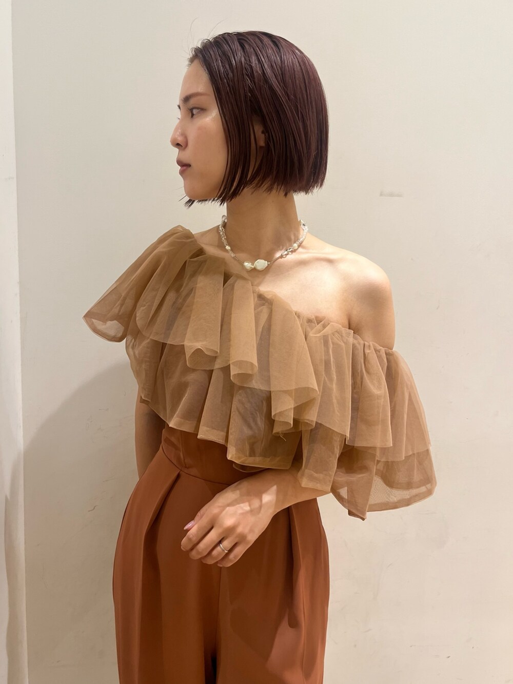 ブラック系のパンプス、オレンジ系のパンツドレス、ブラック系のクラッチバッグを着用したレディースの夏コーディネートの5枚目の写真