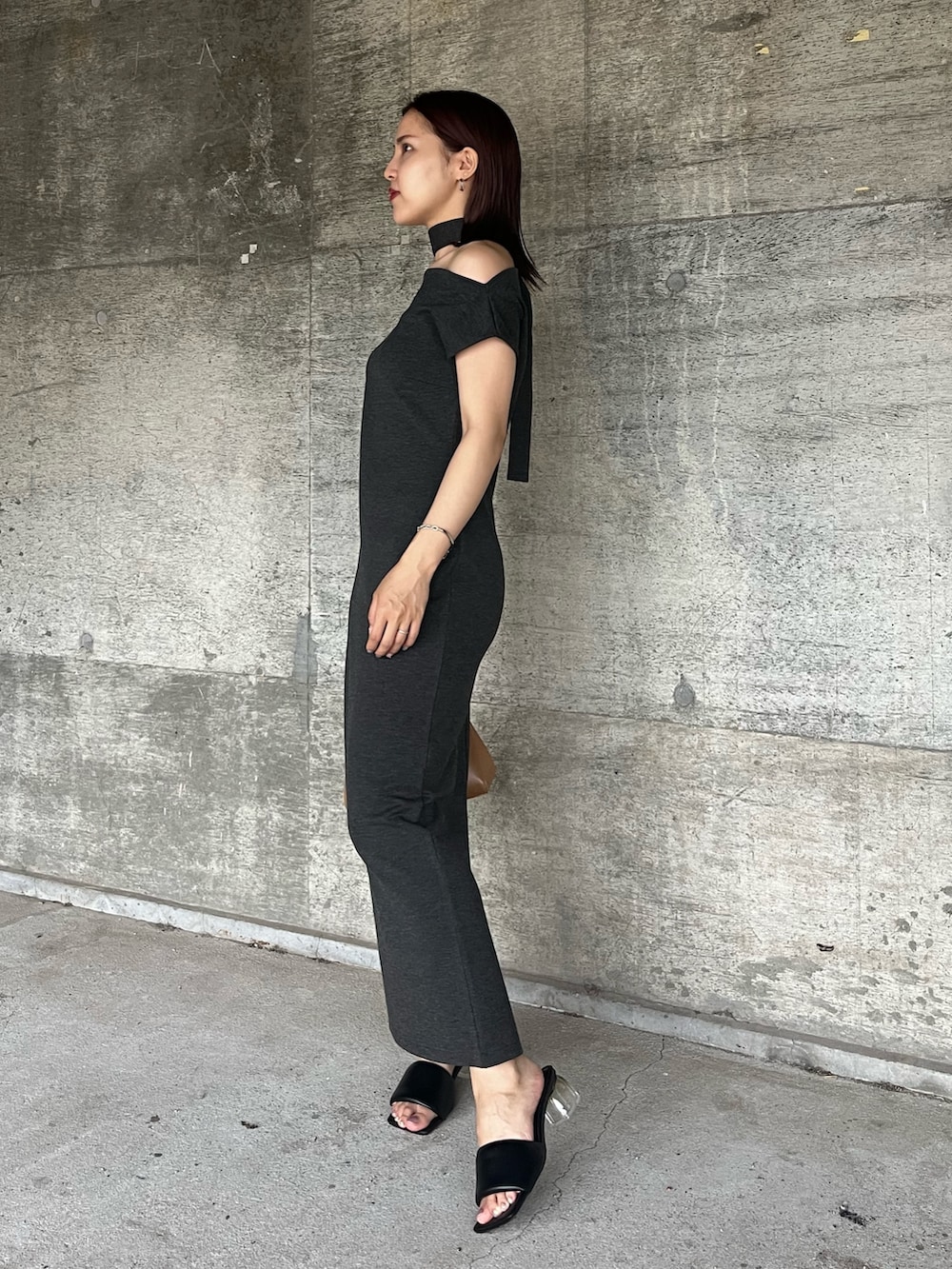 グレー系のワンピース、ブラウン系のハンドバッグ、ブラック系のサンダルを着用したレディースの夏コーディネートの2枚目の写真