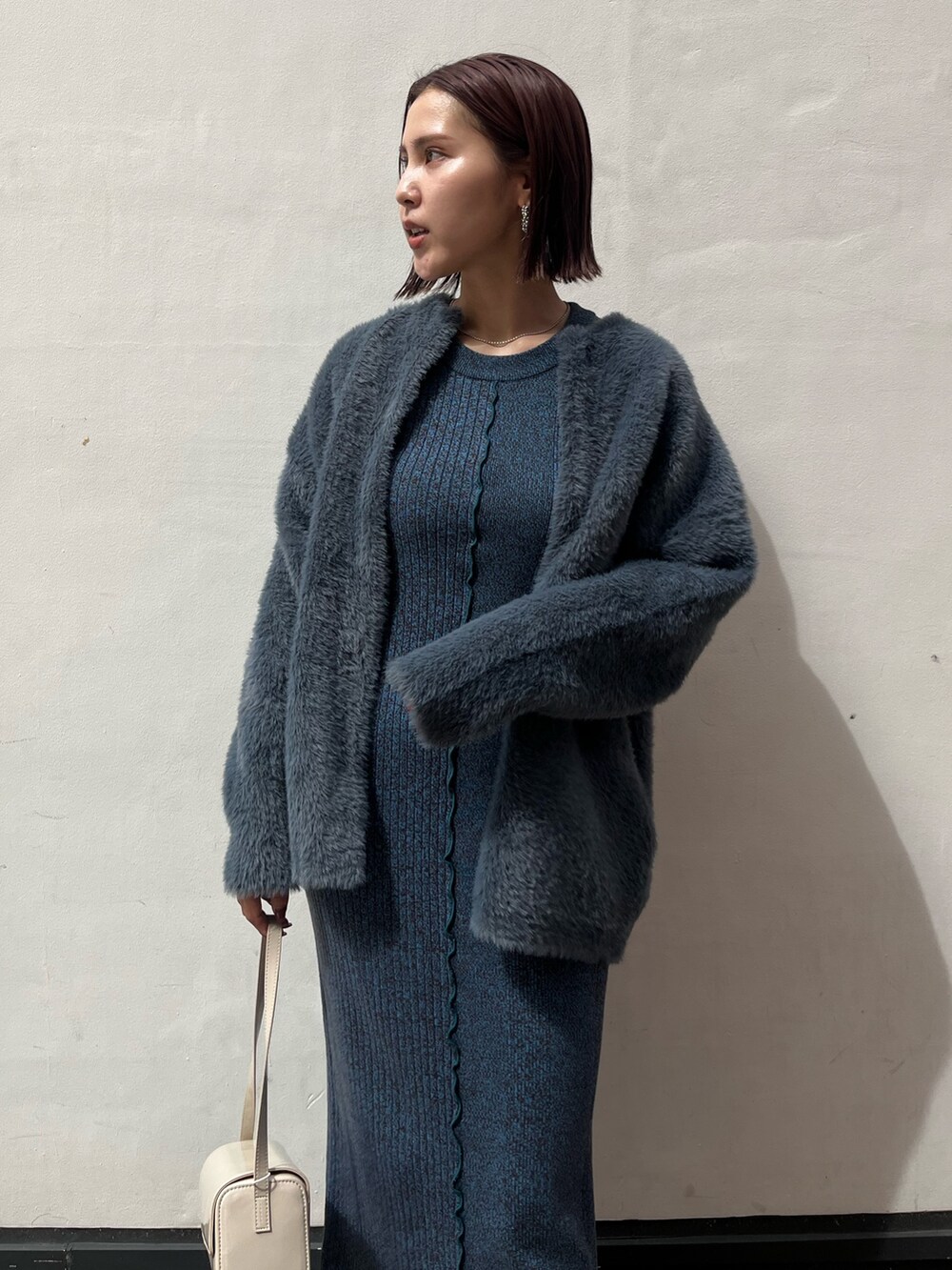 ブラック系のブーツ、ホワイト系のショルダーバッグ、ブルー系のワンピースを着用したレディースの秋コーディネートの4枚目の写真