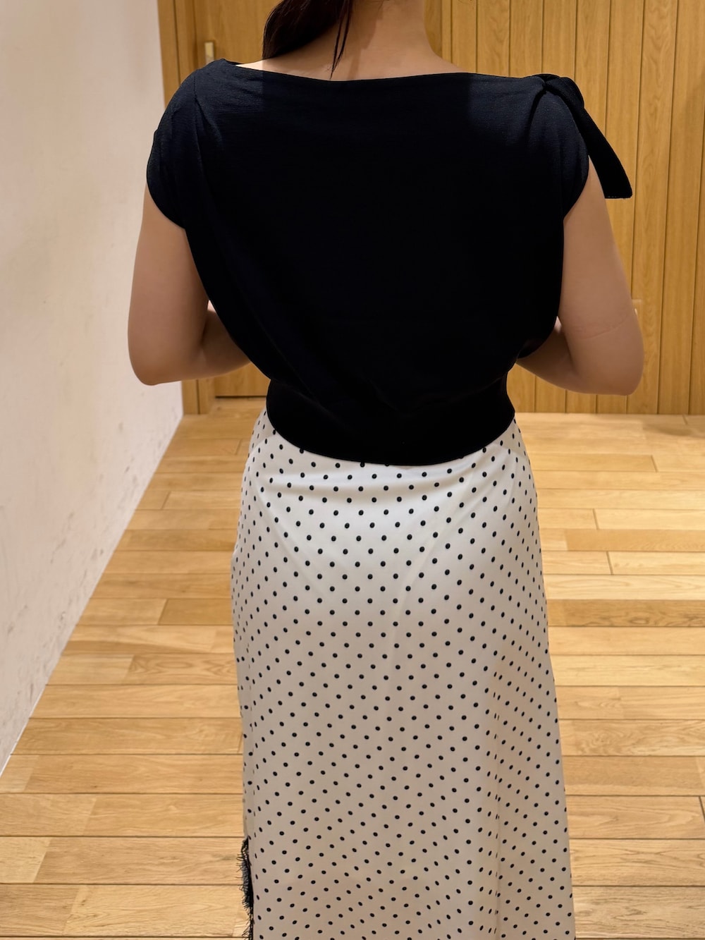 ブラック系のパンプス、ブラック系のニット/セーター、ホワイト系のスカートを着用したレディースの夏コーディネートの6枚目の写真