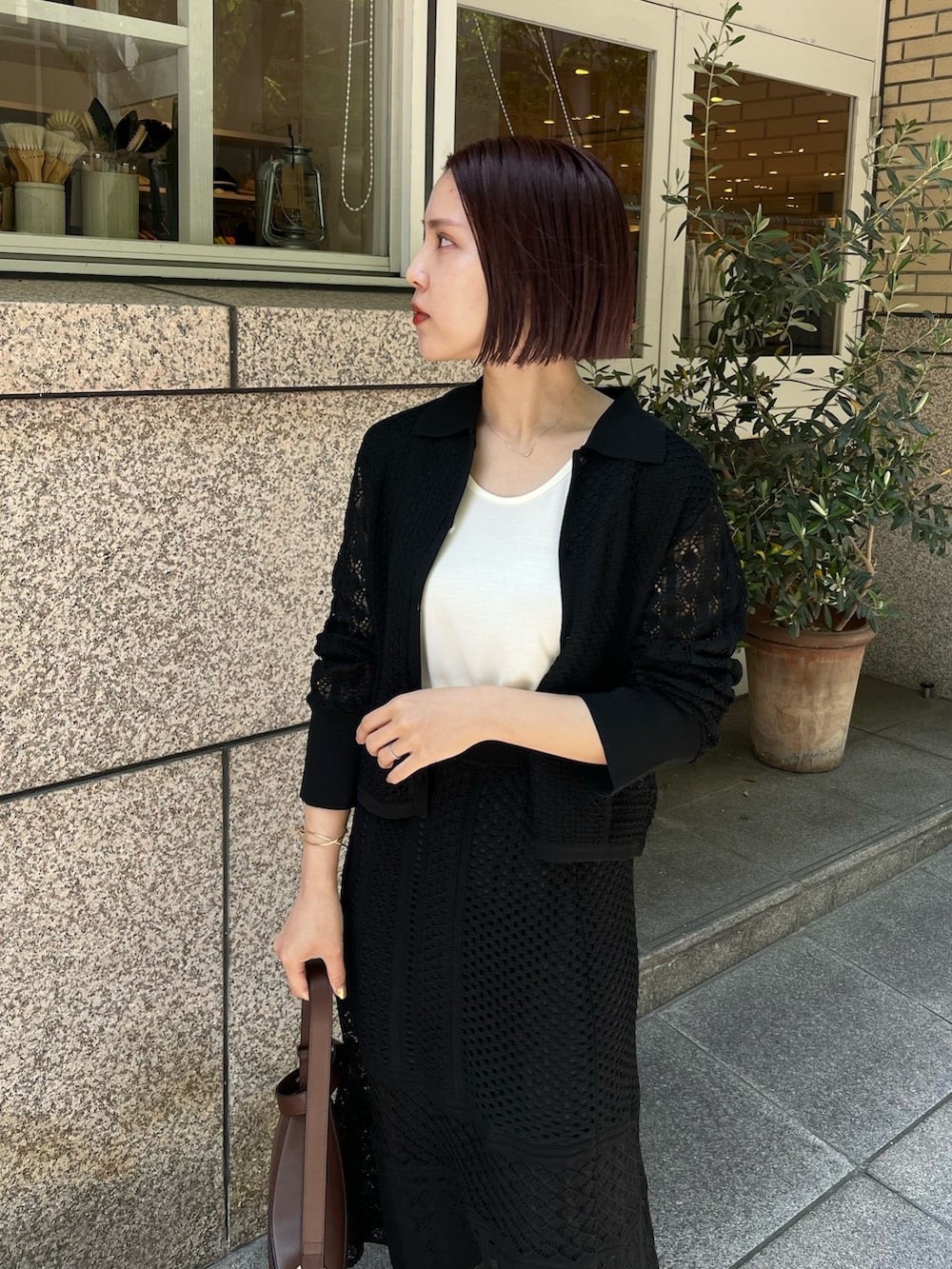 ブラック系のスカート、ブラウン系のショルダーバッグ、イエロー系のサンダルを着用したレディースの春コーディネートの5枚目の写真