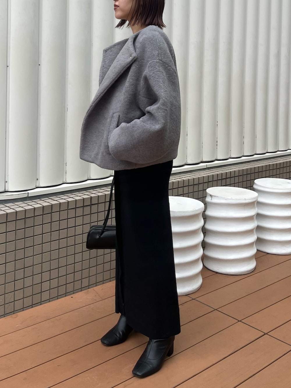 グレー系のブルゾン、ホワイト系のTシャツ/カットソー、ブラック系のショルダーバッグを着用したレディースの秋コーディネートの2枚目の写真