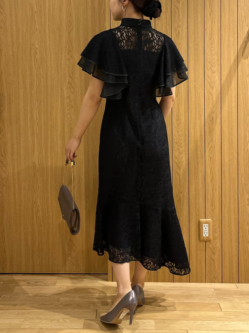 ブラック系のドレス、シルバー系のパンプス、シルバー系のクラッチバッグを着用したレディースの秋コーディネートの3枚目の写真