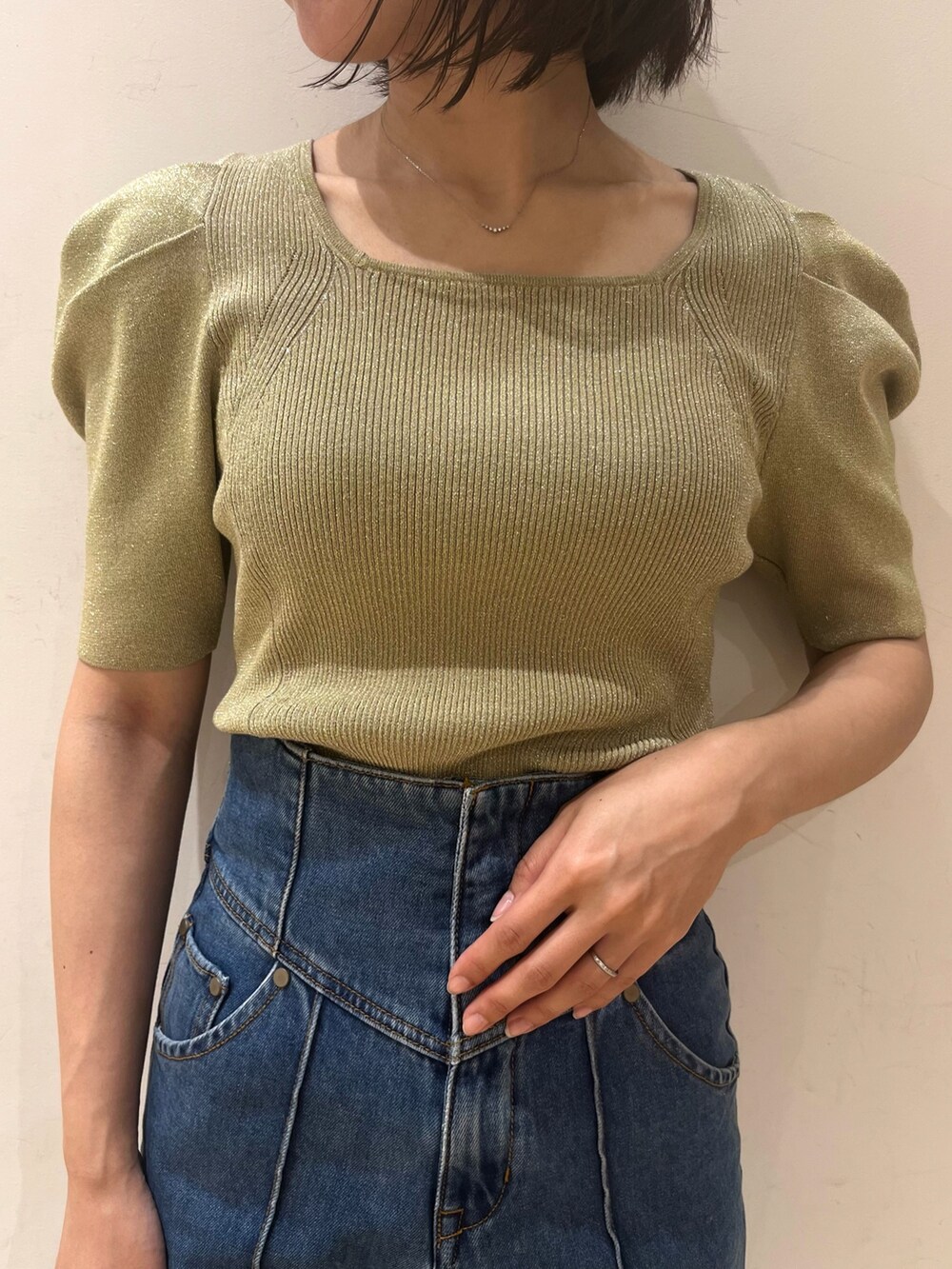 ベージュ系のニット/セーター、ブルー系のデニムパンツ、グリーン系のハンドバッグを着用したレディースの春コーディネートの2枚目の写真