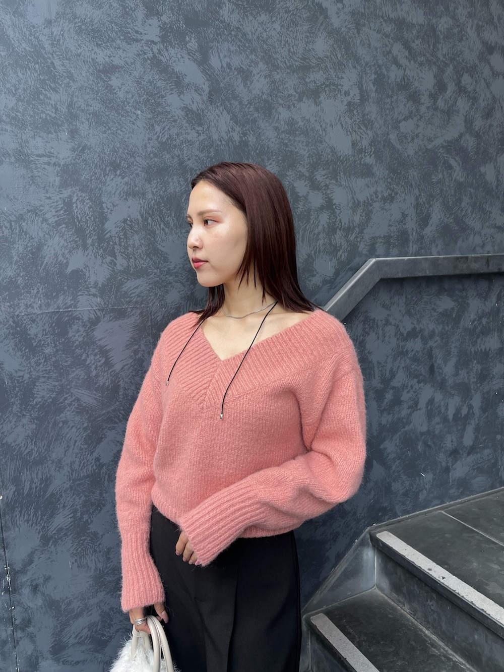 ブラック系のブーツ、ピンク系のニット/セーター、ホワイト系のボストンバッグを着用したレディースの秋コーディネートの6枚目の写真