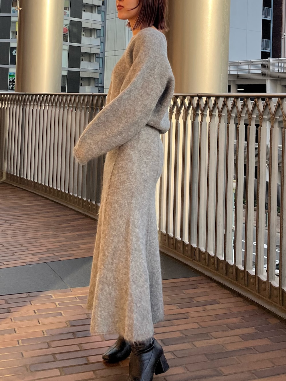 グレー系のスカート、グレー系のニット/セーターを着用したレディースの秋コーディネートの2枚目の写真