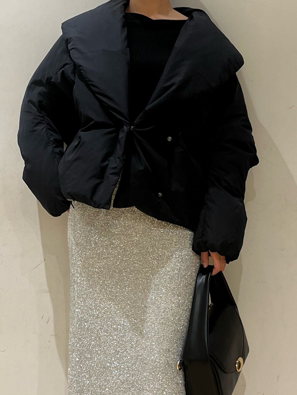 ブラック系のブーツ、ブラック系のハンドバッグ、シルバー系のスカートを着用したレディースの冬コーディネートの6枚目の写真