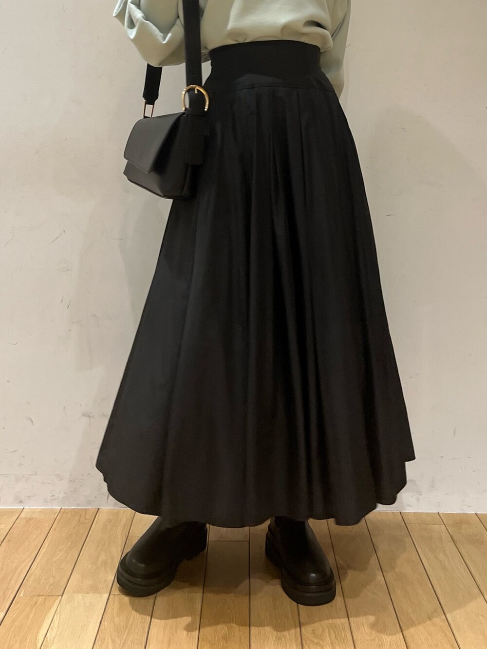 ブラック系のブーツ、ブラック系のスカート、グリーン系のニット/セーターを着用したレディースの冬コーディネートの6枚目の写真