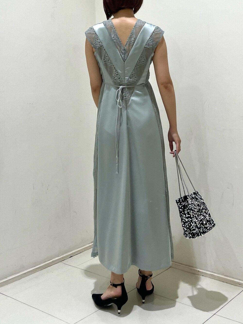 シルバー系のハンドバッグ、ブラック系のパンプス、グリーン系のドレスを着用したレディースの秋コーディネートの3枚目の写真