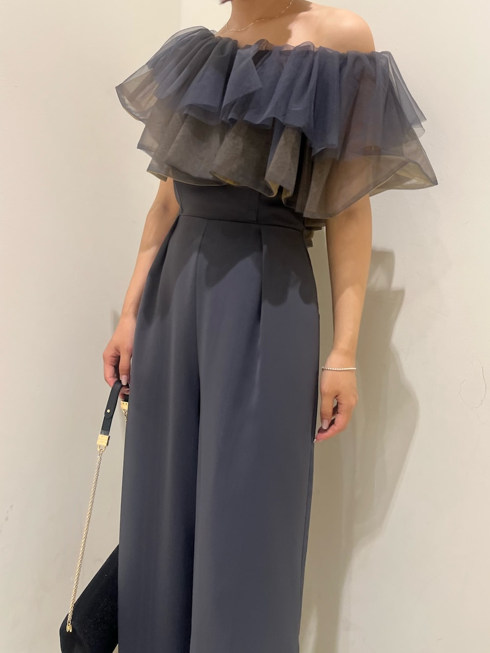 ブラック系のパンプス、ブラック系のクラッチバッグ、グレー系のパンツドレスを着用したレディースの夏コーディネートの7枚目の写真