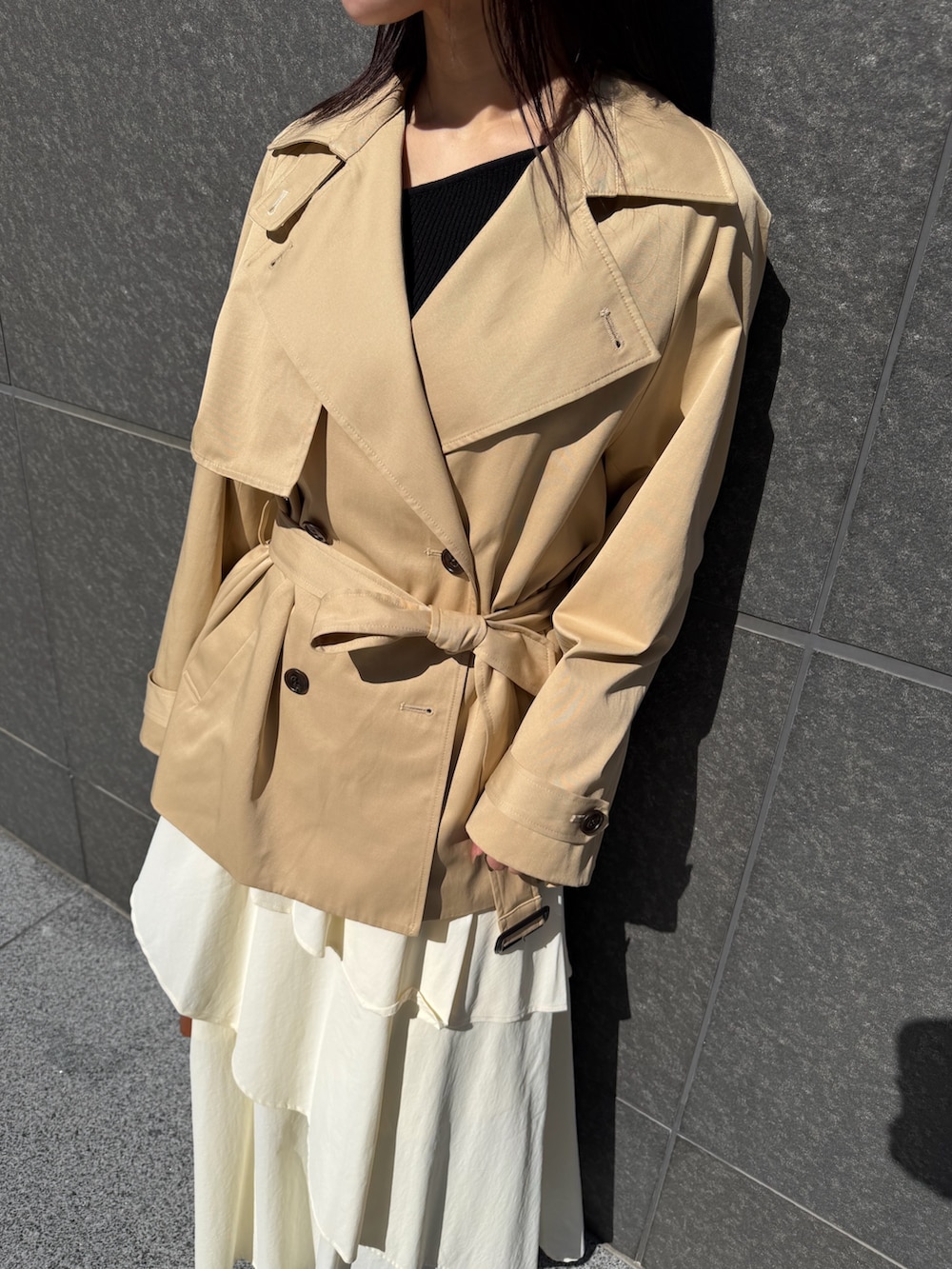 ベージュ系のトレンチコート、ホワイト系のスカート、ブラウン系のハンドバッグを着用したレディースの冬コーディネートの7枚目の写真