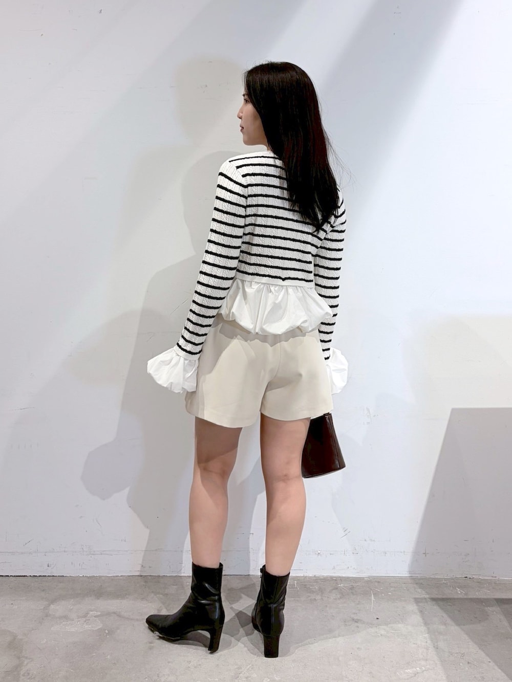 ホワイト系のその他パンツ、ブラック系のブーツ、ブラウン系のハンドバッグを着用したレディースの夏コーディネートの3枚目の写真