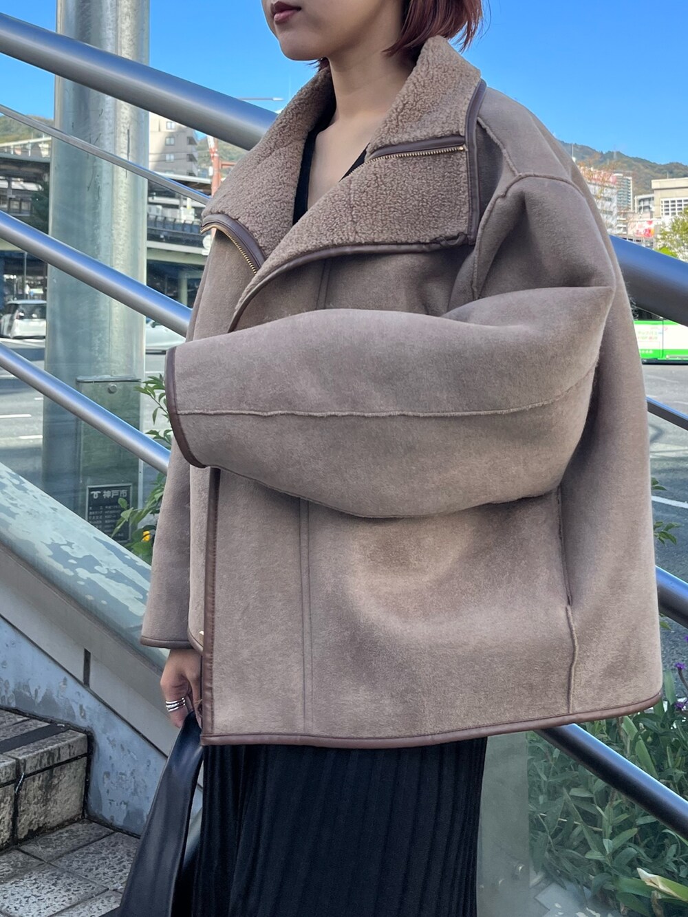 ブラック系のワンピース、ベージュ系のブーツ、ブラック系のハンドバッグを着用したレディースの秋コーディネートの5枚目の写真