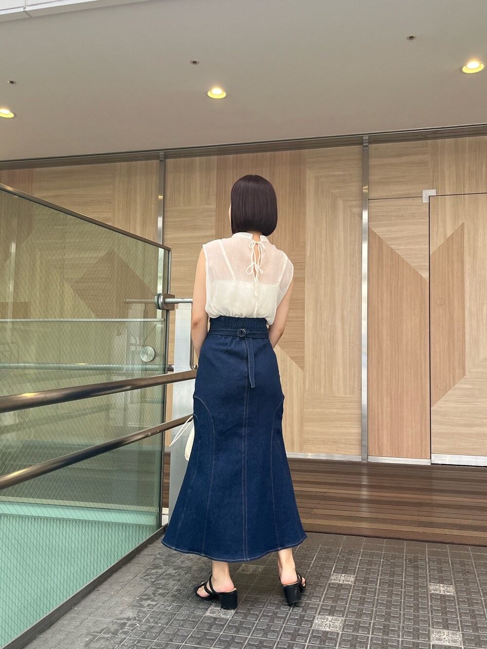 ブルー系のシャツ/ブラウス、ブルー系のデニムスカート、ベージュ系のハンドバッグを着用したレディースの夏コーディネートの6枚目の写真