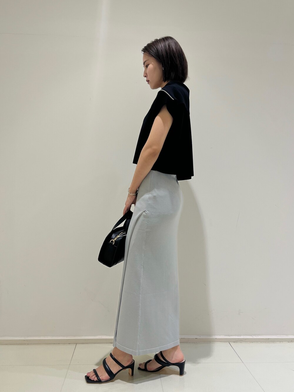 ブラック系のショルダーバッグ、ブラック系のサンダル、ブルー系のスカートを着用したレディースの春コーディネートの3枚目の写真