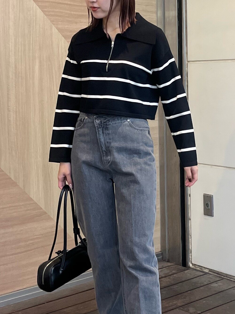 ブラック系のデニムパンツ、ブラック系のニット/セーター、ブラック系のショルダーバッグを着用したレディースの冬コーディネートの7枚目の写真
