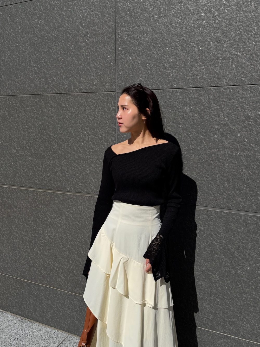 ホワイト系のスカート、ブラック系のニット/セーター、ブラウン系のハンドバッグを着用したレディースの冬コーディネートの4枚目の写真