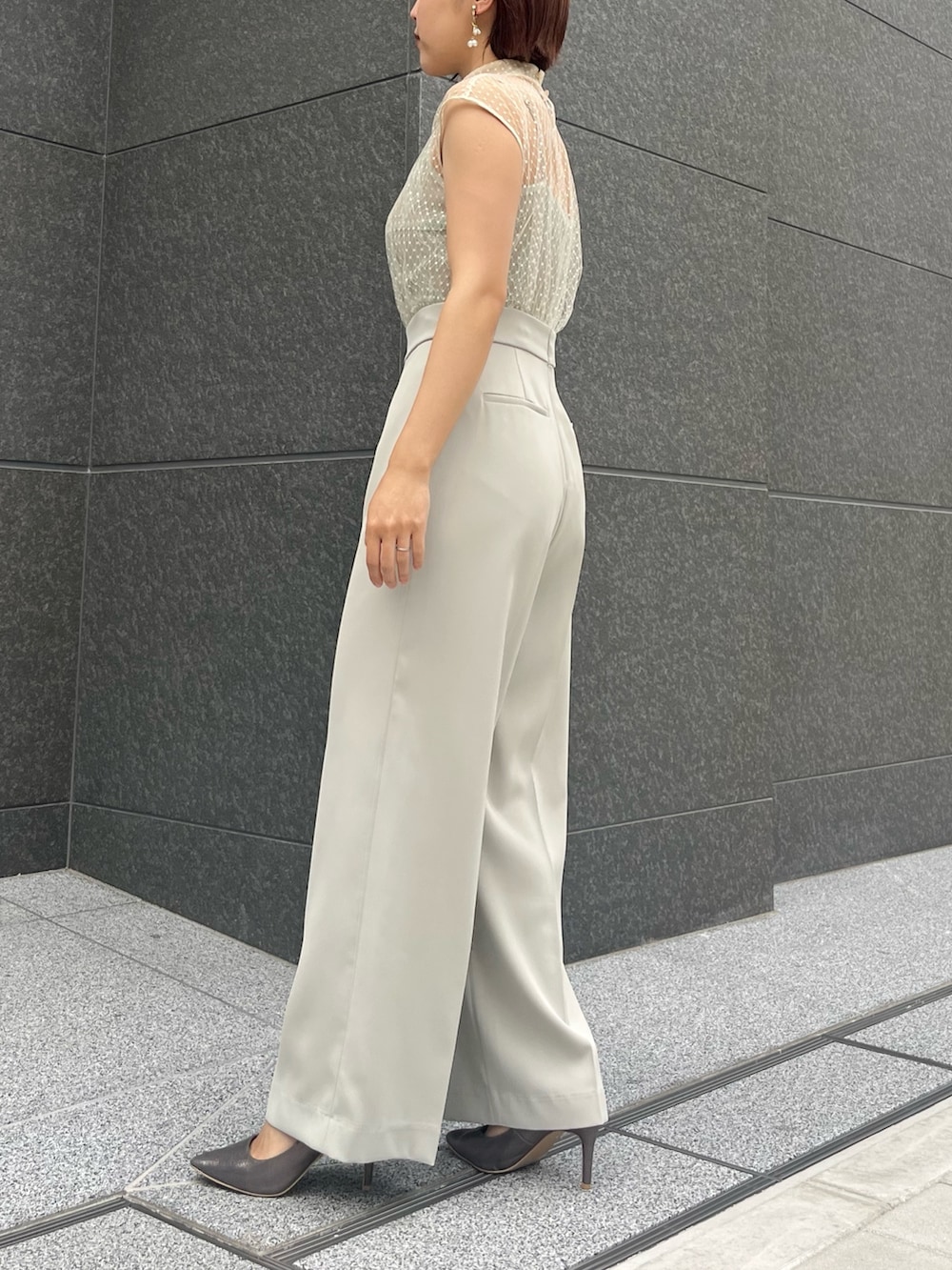 シルバー系のハンドバッグ、シルバー系のパンプス、グリーン系のパンツドレスを着用したレディースの春コーディネートの3枚目の写真