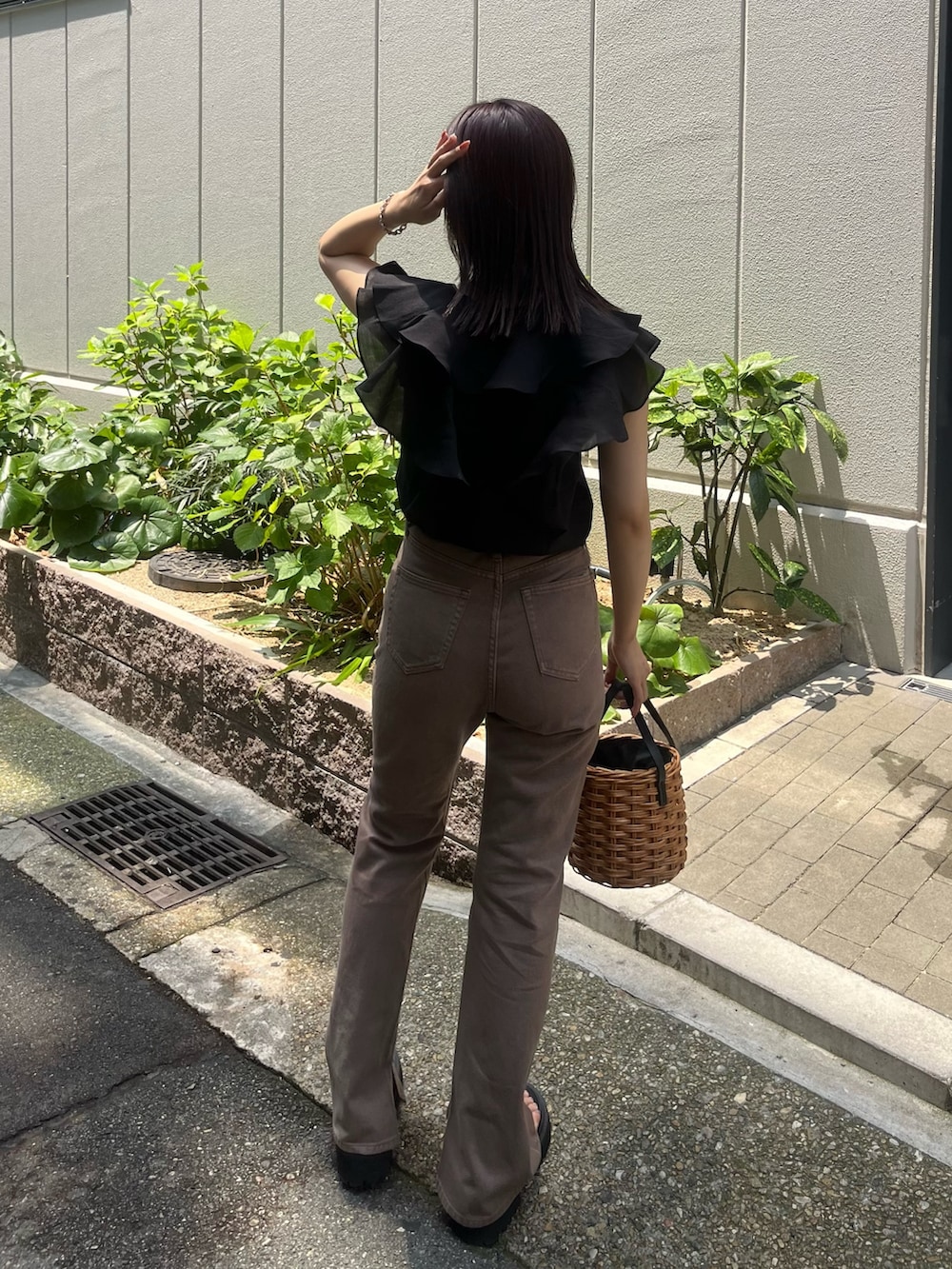 ベージュ系のデニムパンツ、ブラウン系のハンドバッグ、ブラック系のシャツ/ブラウスを着用したレディースの夏コーディネートの3枚目の写真