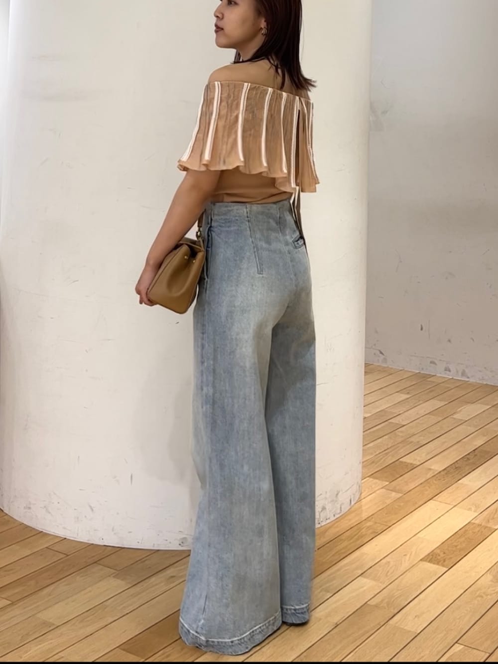 ブルー系のデニムパンツ、ホワイト系のサンダル、ブラウン系のハンドバッグを着用したレディースの春コーディネートの2枚目の写真