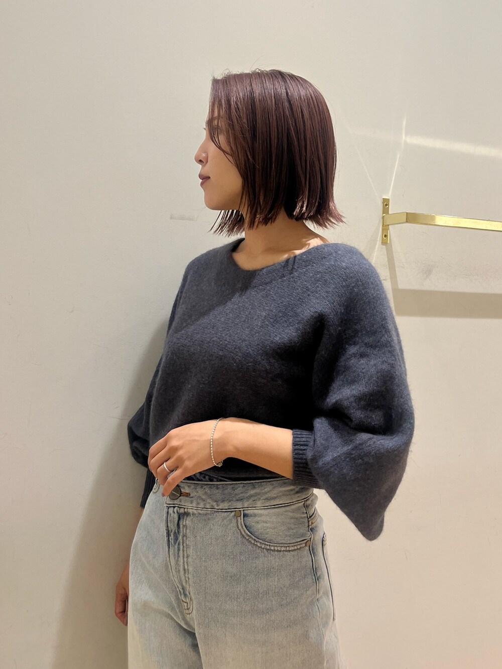 グレー系のニット/セーター、ブルー系のデニムパンツ、ブラック系のショルダーバッグを着用したレディースの秋コーディネートの5枚目の写真