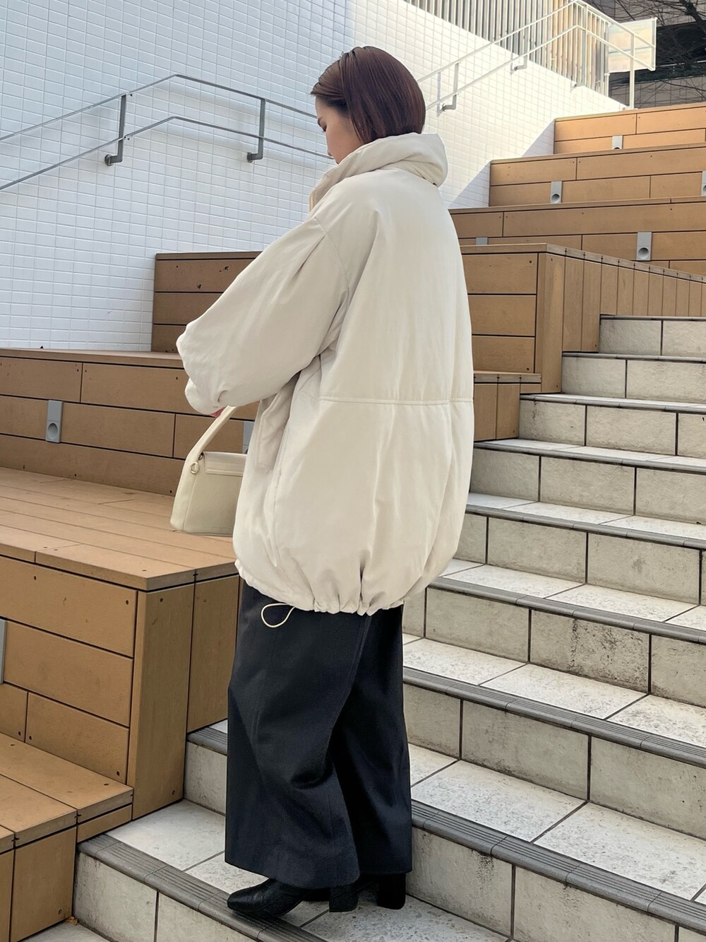 グレー系のその他パンツ、ホワイト系のハンドバッグ、ホワイト系のダウンジャケット/コートを着用したレディースの冬コーディネートの2枚目の写真