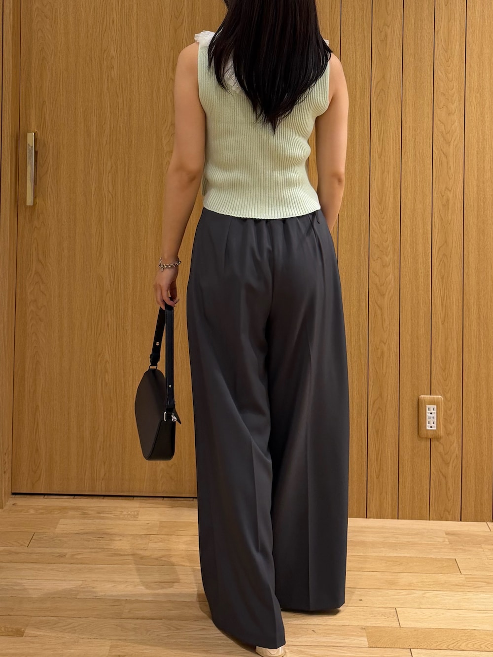 グレー系のその他パンツ、ブラック系のハンドバッグ、グリーン系のニット/セーターを着用したレディースの夏コーディネートの3枚目の写真