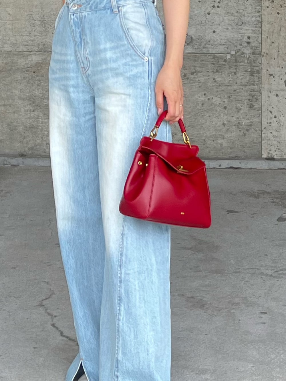 ブルー系のデニムパンツ、ブルー系のニット/セーター、レッド系のハンドバッグを着用したレディースの春コーディネートの6枚目の写真