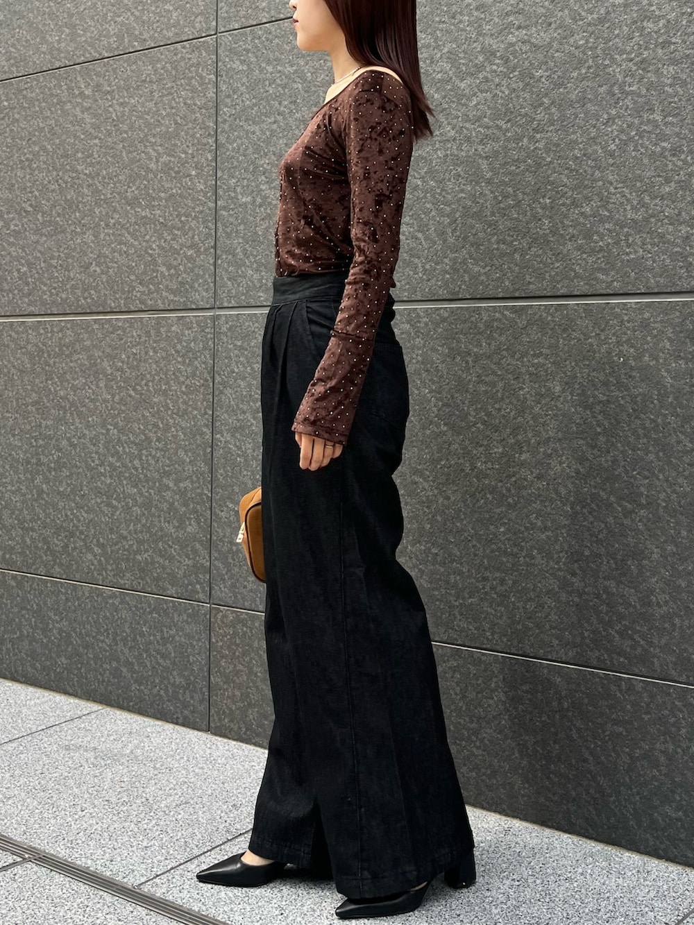 ブラック系のデニムパンツ、ブラウン系のハンドバッグ、ブラウン系のTシャツ/カットソーを着用したレディースの秋コーディネートの2枚目の写真