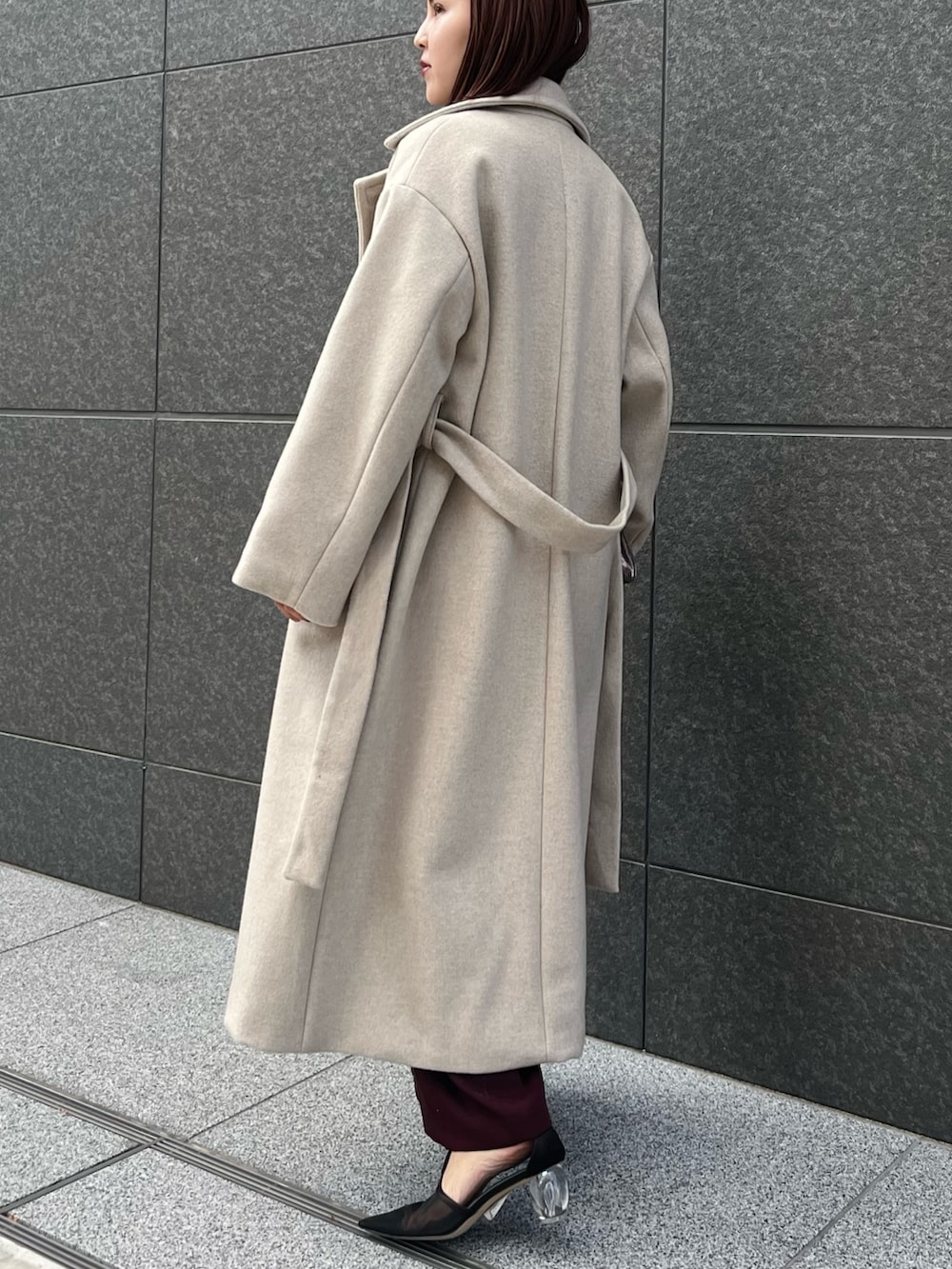 レッド系のパンツドレス、ホワイト系のチェスターコートを着用したレディースの冬コーディネートの3枚目の写真