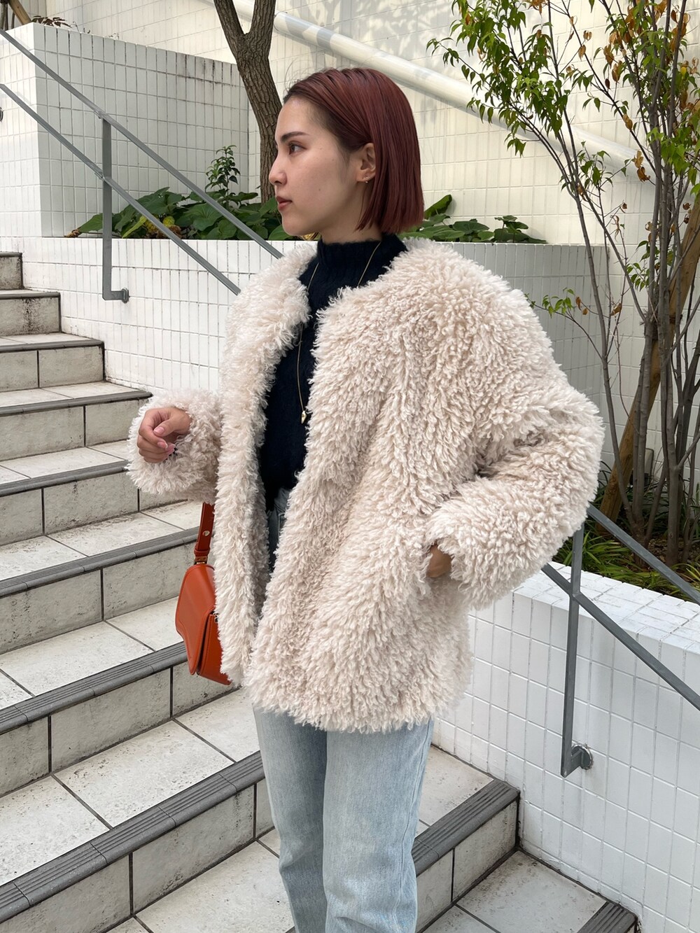 ブルー系のニット/セーター、ホワイト系のその他アウター、ブルー系のデニムパンツを着用したレディースの秋コーディネートの3枚目の写真