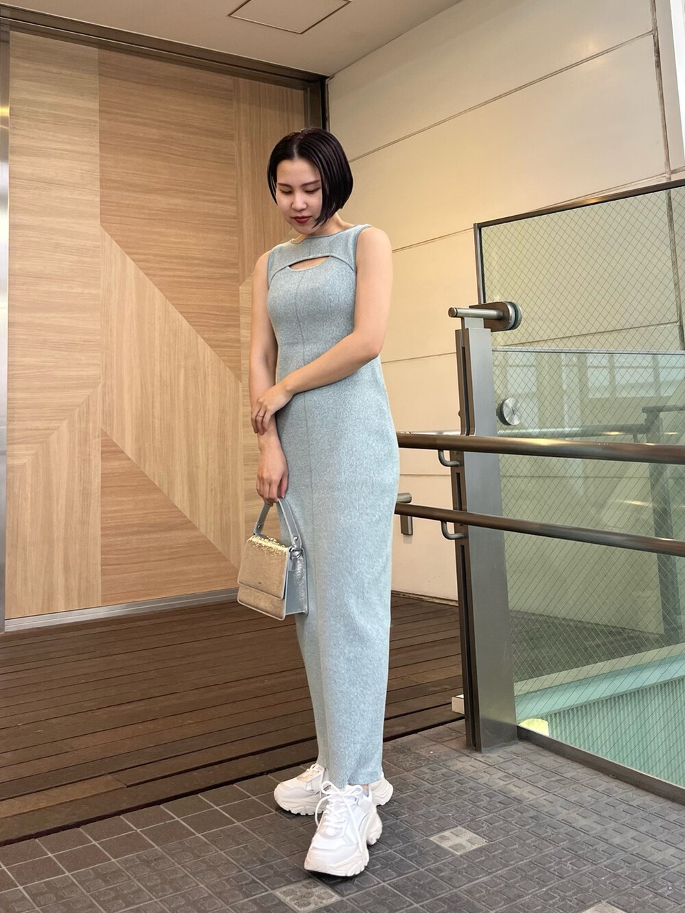 シルバー系のショルダーバッグ、ホワイト系のスニーカー、ブルー系のワンピースを着用したレディースの春コーディネートの4枚目の写真