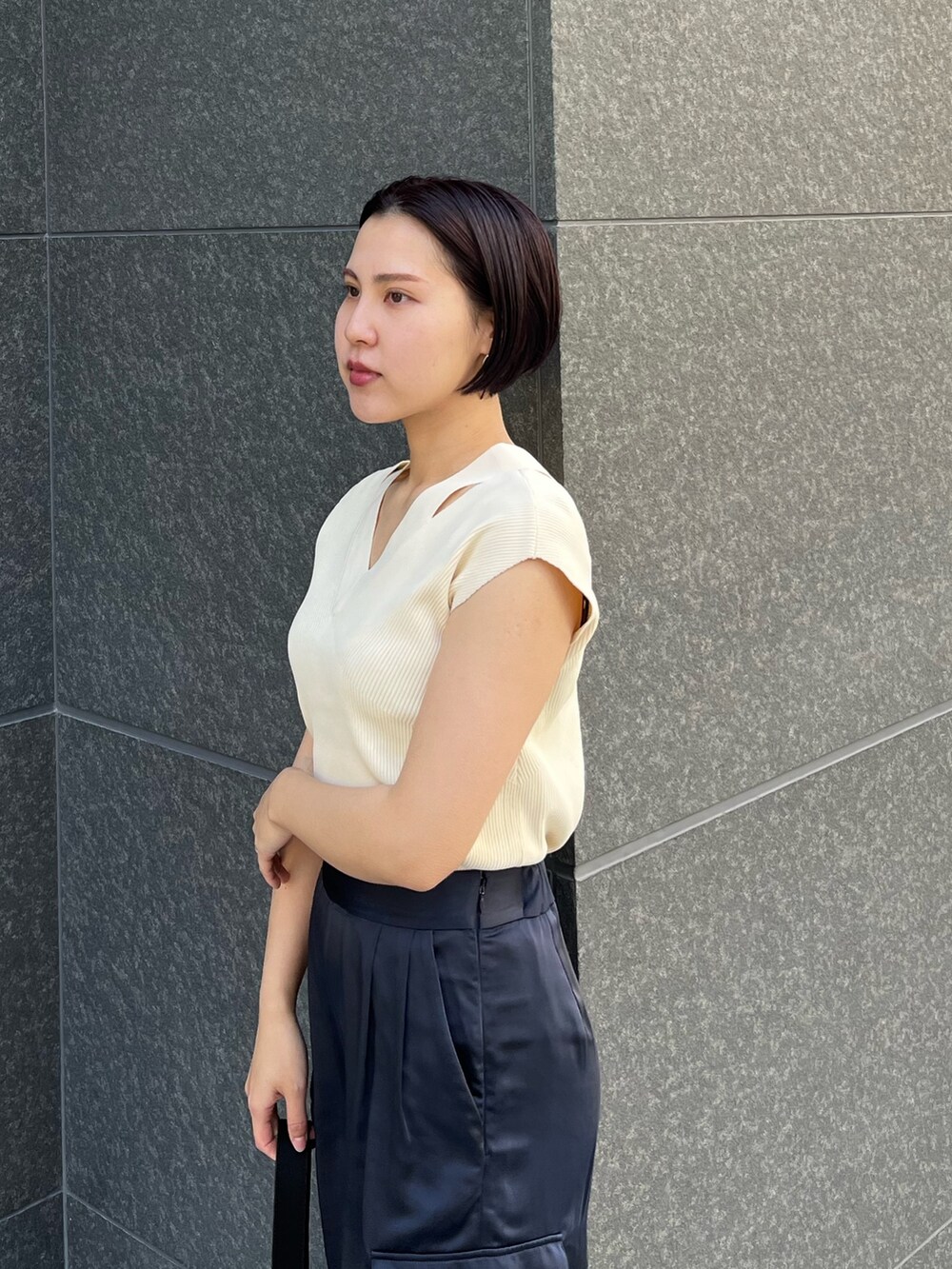 ブラック系のハンドバッグ、ブルー系のカーゴパンツ、ホワイト系のニット/セーターを着用したレディースの春コーディネートの6枚目の写真